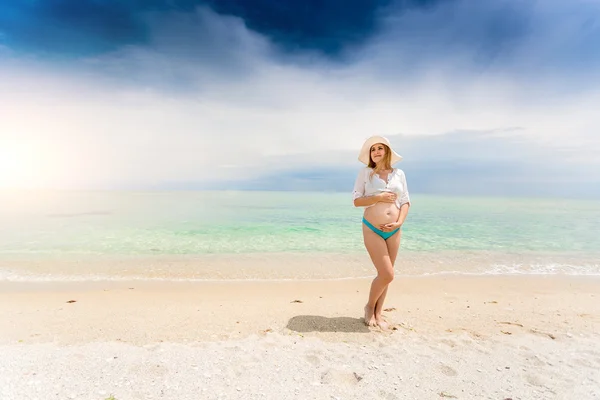 Pregnant woman posing seashore and holding hands on abdomen — Stock Photo, Image