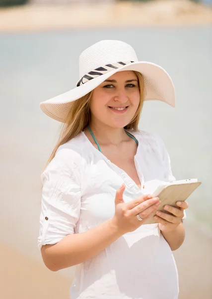 Mujer feliz posando con tableta digital en la playa ventosa —  Fotos de Stock