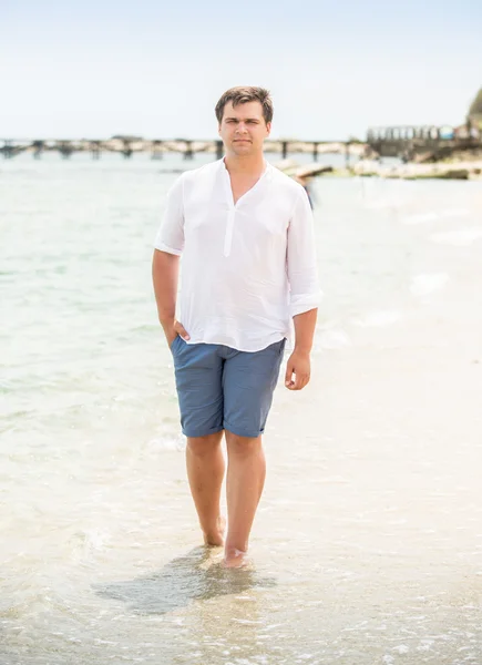 Bonito homem de camisa branca andando na praia — Fotografia de Stock