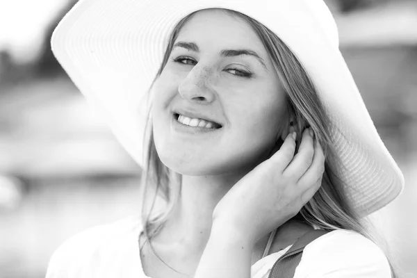 Mooie vrouw in witte hoed met toothy glimlach die zich voordeed op strand — Stockfoto