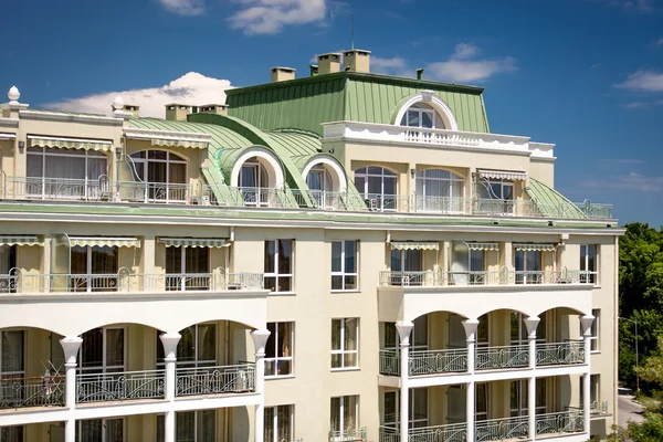 Классическое здание с дугами и балконами и зеленой металлической крышей — стоковое фото