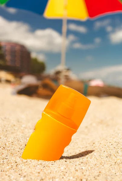 Foto tonificada de loción bronceadora en la playa de arena en el día soleado —  Fotos de Stock