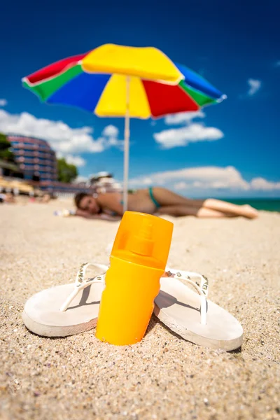 Primer plano de chanclas y bloqueador solar en la playa —  Fotos de Stock