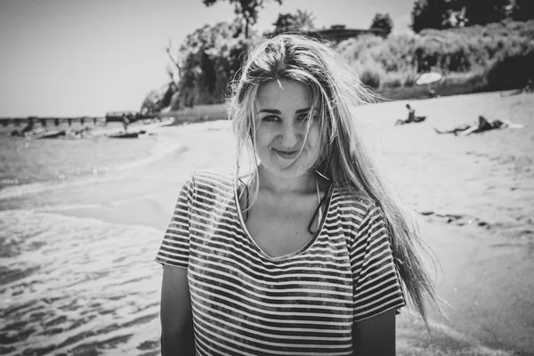 Roztomilá žena s dlouhými vlasy v košili pruhovaný námořník pózuje na pláži — Stock fotografie