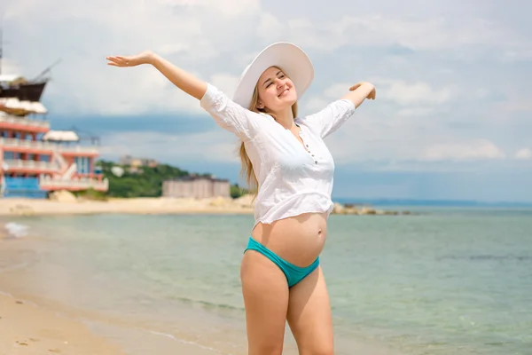 Lachende zwangere vrouw permanent op strand met open armen — Stockfoto