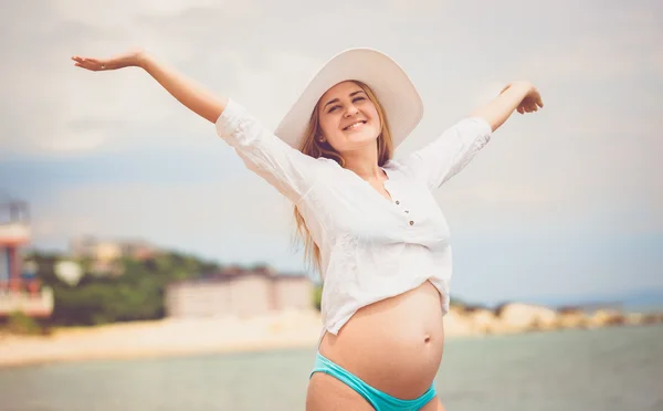 Szczęśliwy w ciąży kobieta w białej koszuli ciesząc się słońcem na plaży — Zdjęcie stockowe