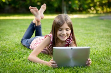 mutlu çocuk dijital tablet ile çim üzerinde yalan