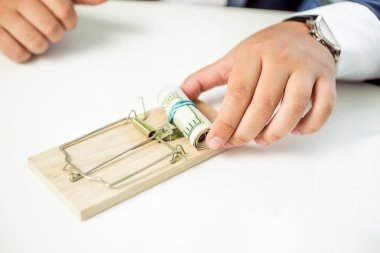 Closeup of businessman taking money out of mousetrap clipart