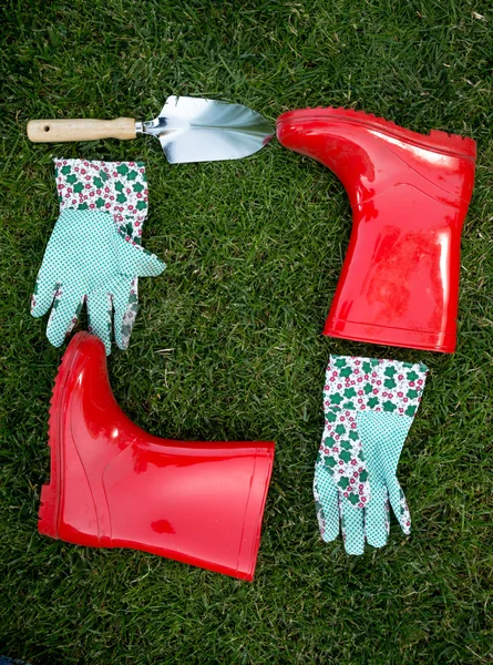 Guantes de jardín, pala y botas de goma roja que yacen sobre hierba verde —  Fotos de Stock