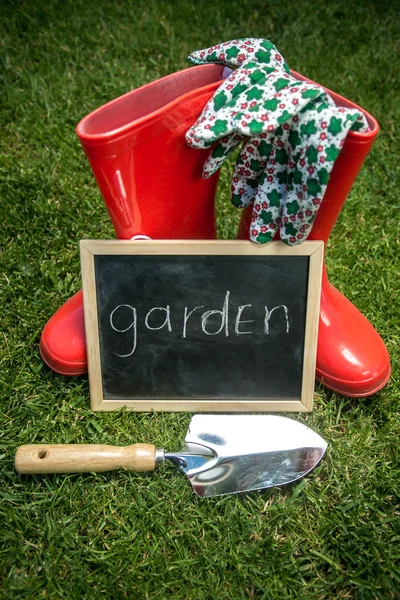 Quadro negro na grama ao lado de ferramentas de jardim com texto "Jardim " — Fotografia de Stock