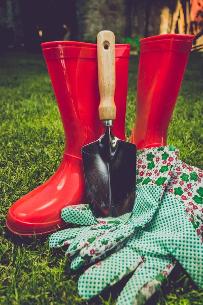 Toned filter of garden tools and red boots on meadow — Stock Photo, Image