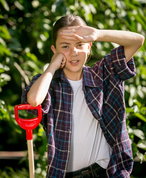 Tired girl leaning on shovel after work at garden — Stock Photo, Image