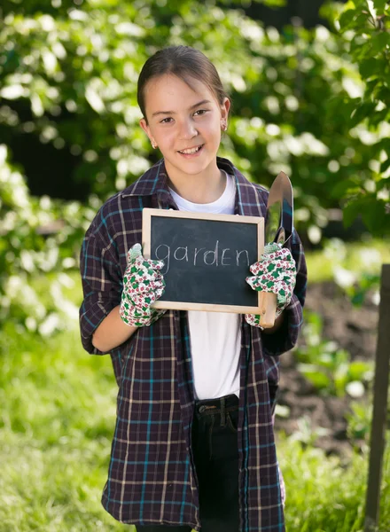 Chica sonriente feliz sosteniendo pizarra con la palabra "Jardín " — Foto de Stock