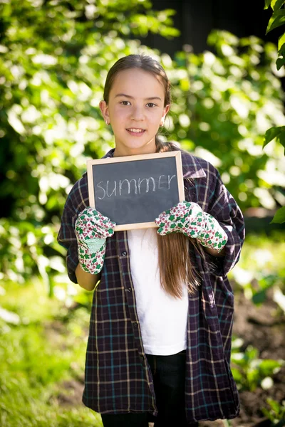 Brünettes Mädchen hält Kreidetafel mit dem Wort "Sommer" im Garten — Stockfoto