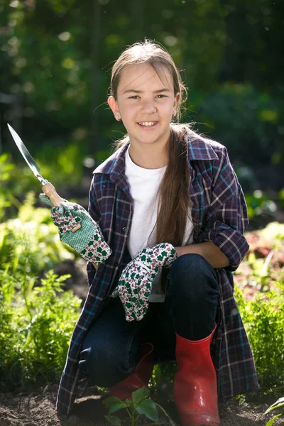 Linda chica sonriente en guantes y botas de goma posando en el jardín — Foto de Stock