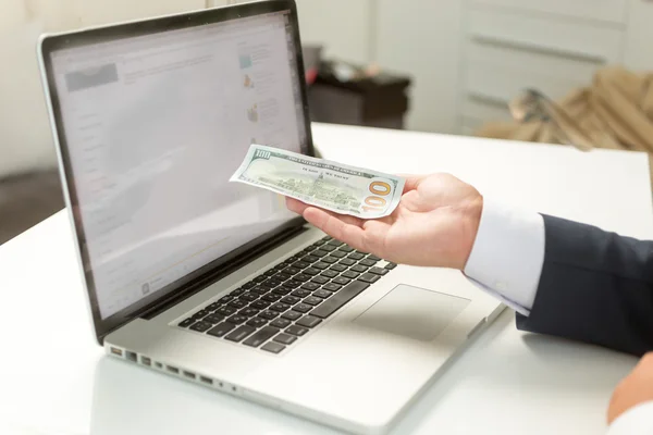 Empresário segurando nota na mão e entregando-a ao computador — Fotografia de Stock