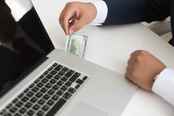 Closeup of an in suit inserting hundred dollar bill in the lapto — Stock Photo, Image