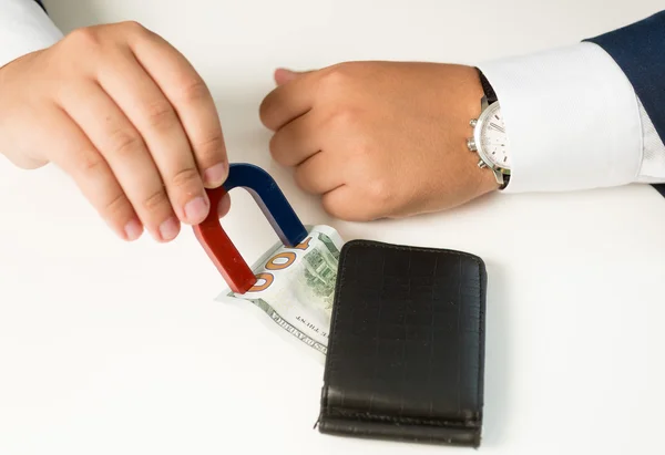 Closeup of man in suit pulling money out wallet with magnet — Stock Photo, Image