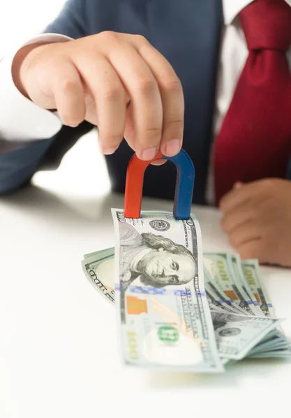 Geschäftsmann hält Magnet in der Hand und zieht Geld vom Tisch — Stockfoto