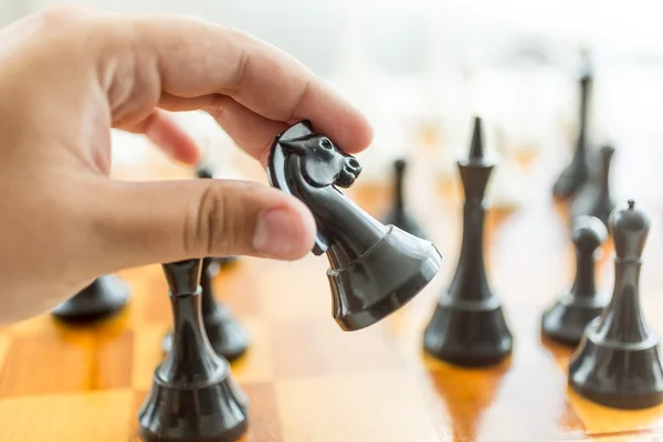 Primer plano de mano masculina sosteniendo pieza de ajedrez de caballo negro — Foto de Stock