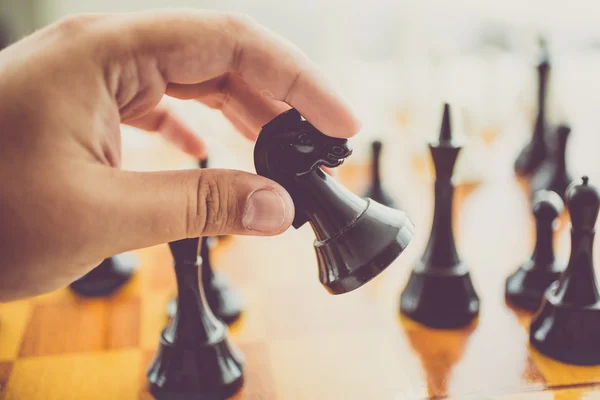 Toned photo of man making move with black horse at chess game — Stock Photo, Image