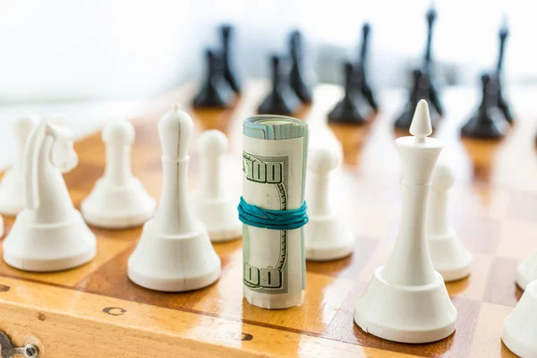 Closeup zkroucené peníze stojí na palubě místo ks klasické šachy — Stock fotografie