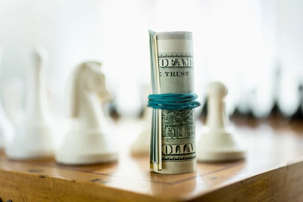 Долларовые купюры, стоящие на шахматной доске вместо башни — стоковое фото