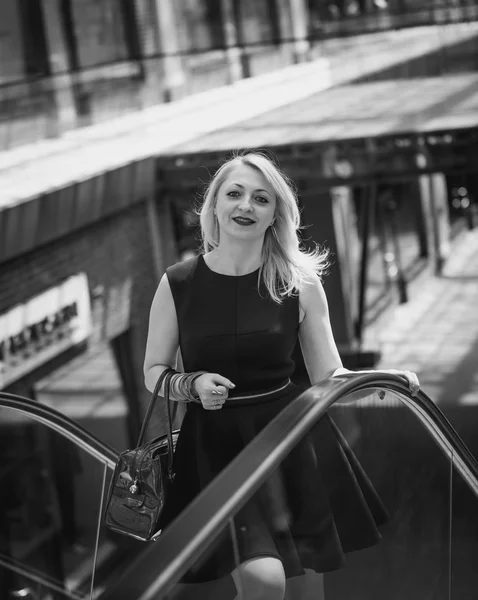 Retrato en blanco y negro de una hermosa mujer posando sobre escaleras mecánicas —  Fotos de Stock