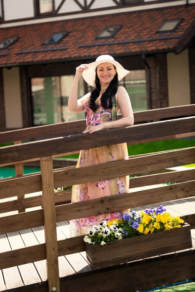 Frau in langem Kleid und weißem Hut geht auf dem alten Holzsteg — Stockfoto