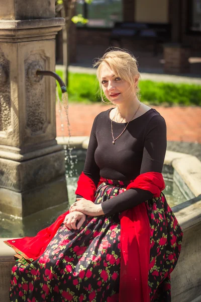 Toned portrait of elegant woman relaxing at old fountain — Stock Photo, Image