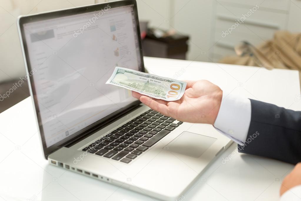 businessman holding banknote on hand and giving it to computer