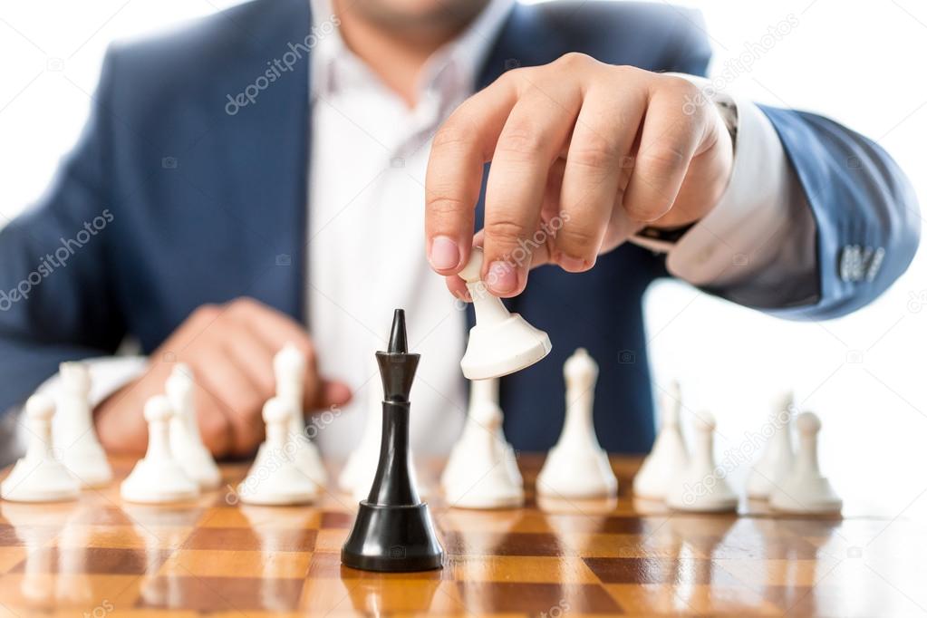 Closeup of businessman playing chess and beating black king