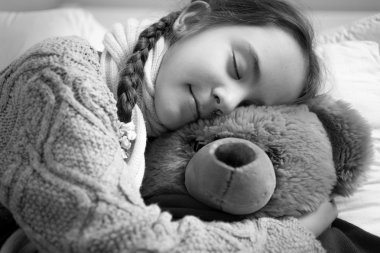 black and white portrait of cute dreaming girl hugging teddy bea