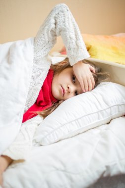 Hasta kız yatakta yatan ve kafasına elini tutarak