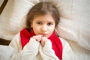 portrait of little sad girl with flu lying in bed