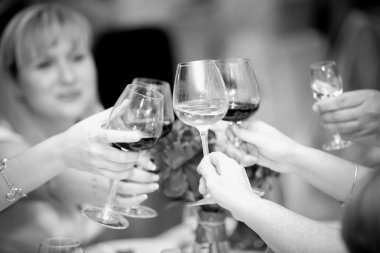 black and white photo of clinking glasses with wine at restauran