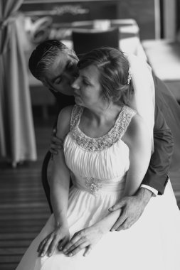 Black and white portrait of groom kissing bride at restaurant
