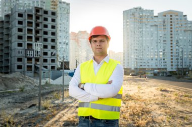 engineer in hardhat posing against building under construction