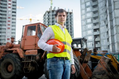 construction inspector posing next to excavator on building site
