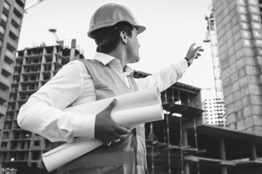 engineer with blueprints checking building site construction