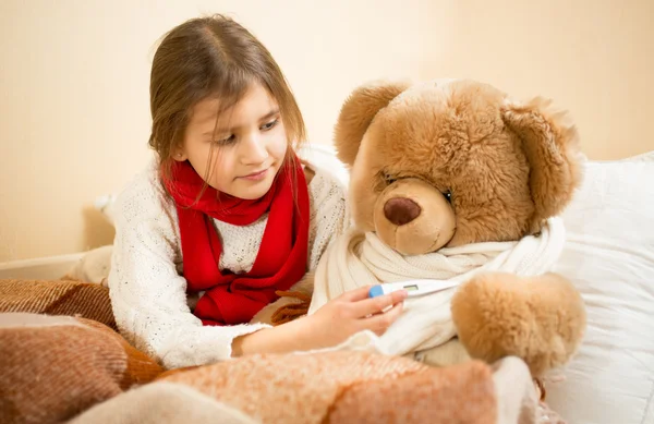 Portrait of girl playing with teddy bear in doctor and patient — Stock Photo, Image