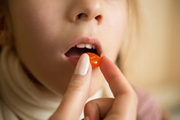 Macro inyección de poco enfermo con la gripe chica tomando píldora en la boca —  Fotos de Stock