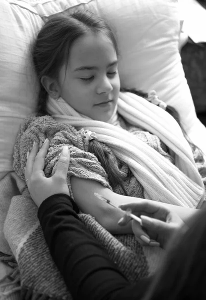 Black and white photo of woman making injection in arm to sick g — 스톡 사진