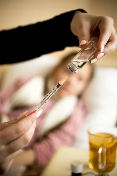 Primer plano de la mujer llenando la jeringa de la ampolla en la cama de la niña enferma — Foto de Stock