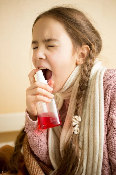 Portrait of sick girl in sweater using throat spray — 스톡 사진