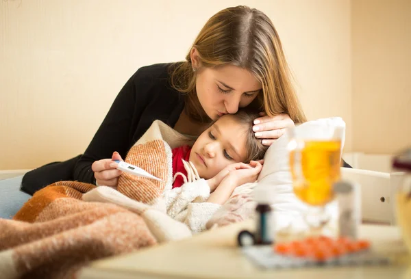 Portrait of caring mother kissing sick daughter in head — Stock fotografie