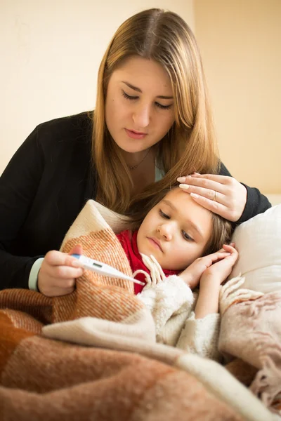 Measuring sick daughter temperature with digital thermometer — Stok fotoğraf