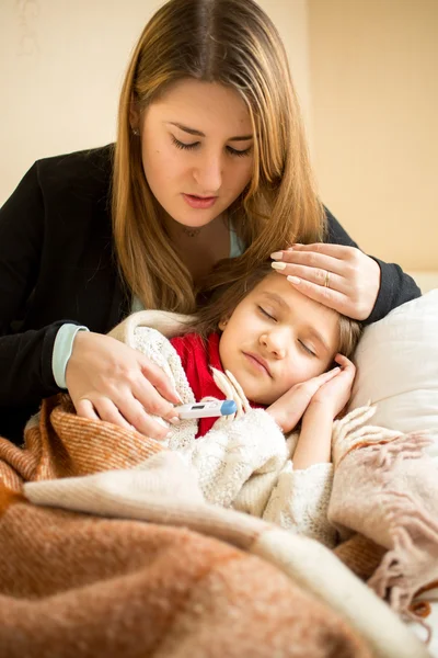 Young mother hugging sick girl in bed — Stok fotoğraf