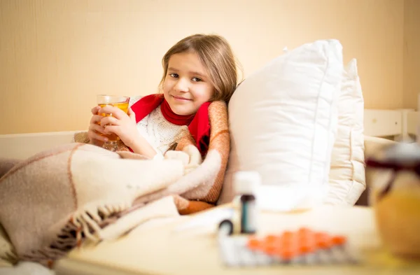 Girl caught flu and drinking hot tea with lemon in bed — Stock Photo, Image