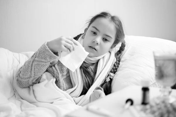 Black and white portrait of sick little girl sneezing in bed — Stock Photo, Image